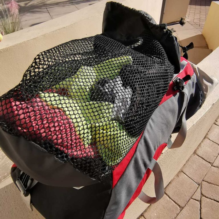 Criterion Large Mesh Storage Bag with dirty washing sitting on top of a rucksack after an outdoor adventure.