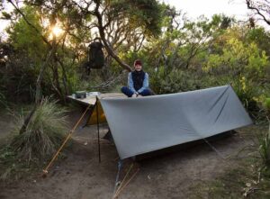 A user of Criterion Sleeping Bags poses for a picture showing his camp in some bushland in Australia